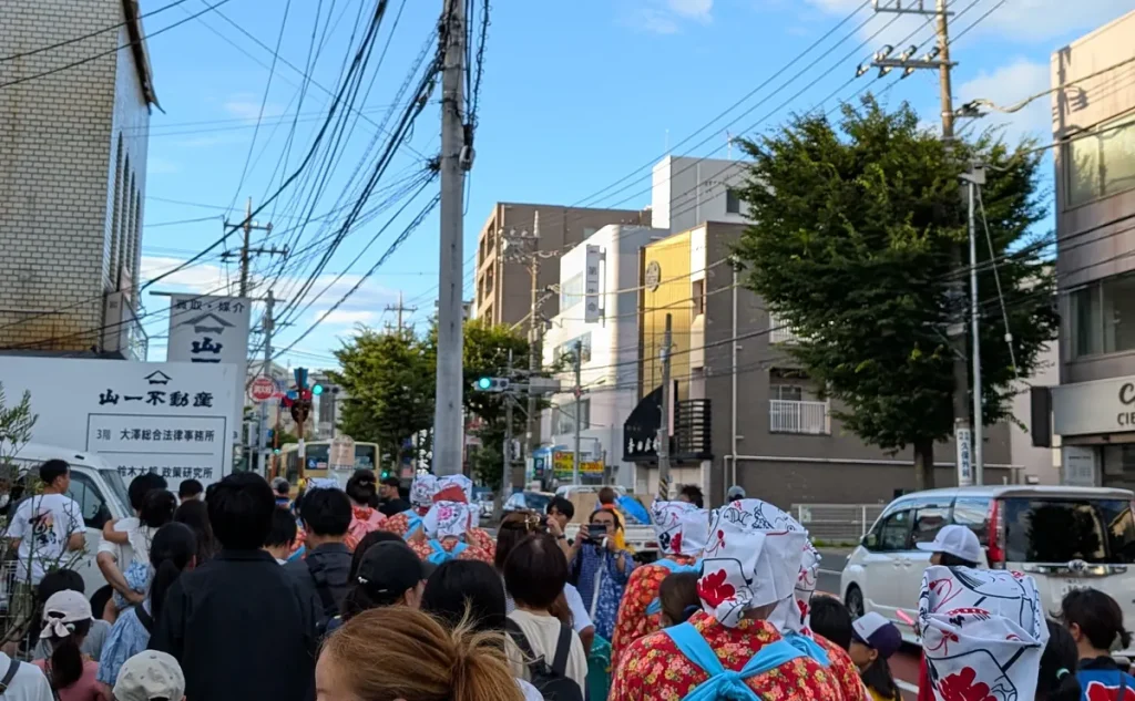 お札まきの行列が花柄の衣装で戸塚の街を練り歩く様子