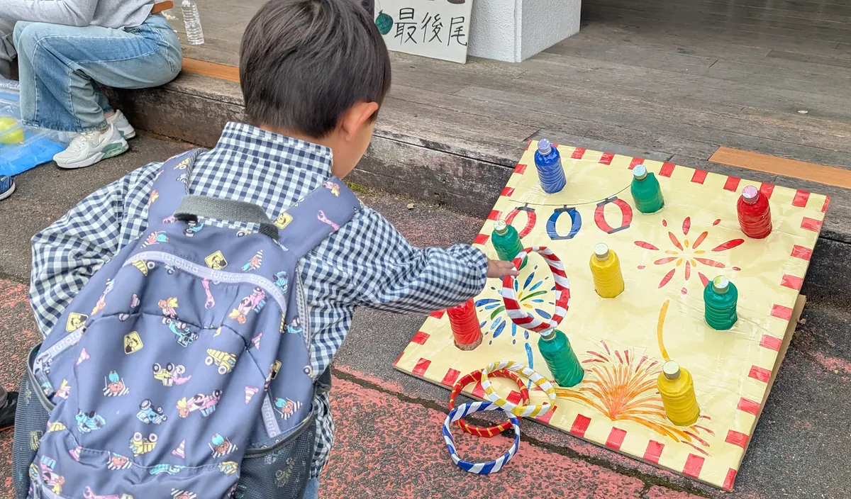 戸塚まつりの縁日で子どもがペットボトル輪投げに挑戦している様子