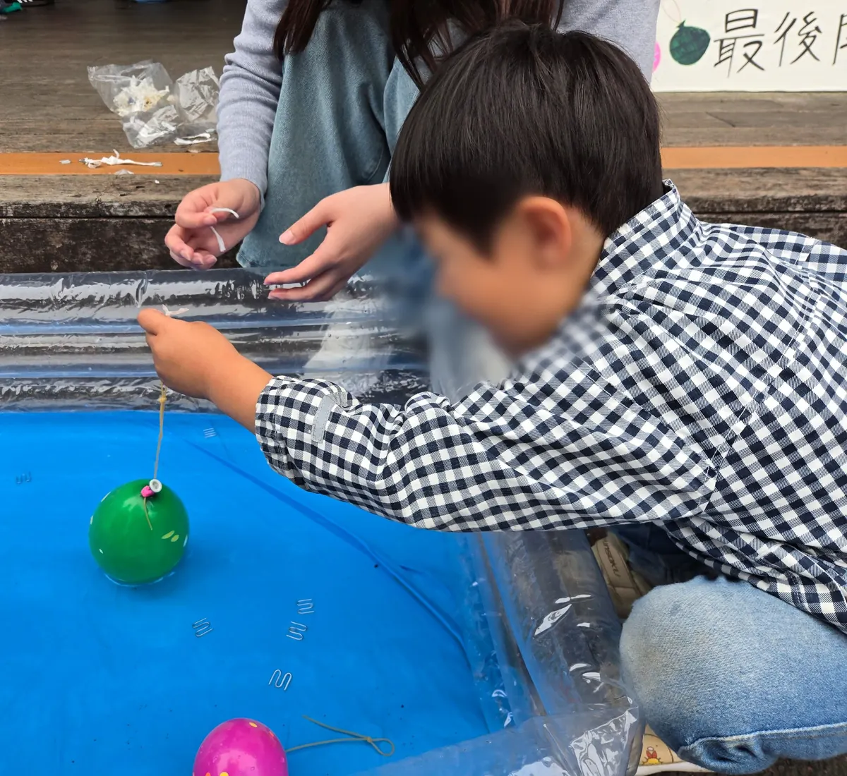 戸塚まつりの縁日で子どもが水ヨーヨー釣りをしている様子