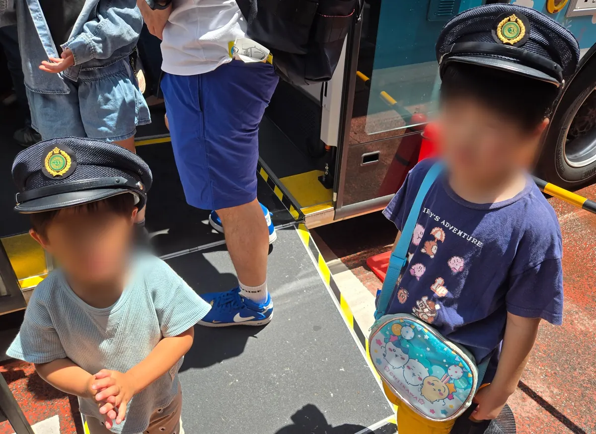 江ノ電バス企画で制帽をかぶった子ども2人がバス乗降口前に並んでいる様子