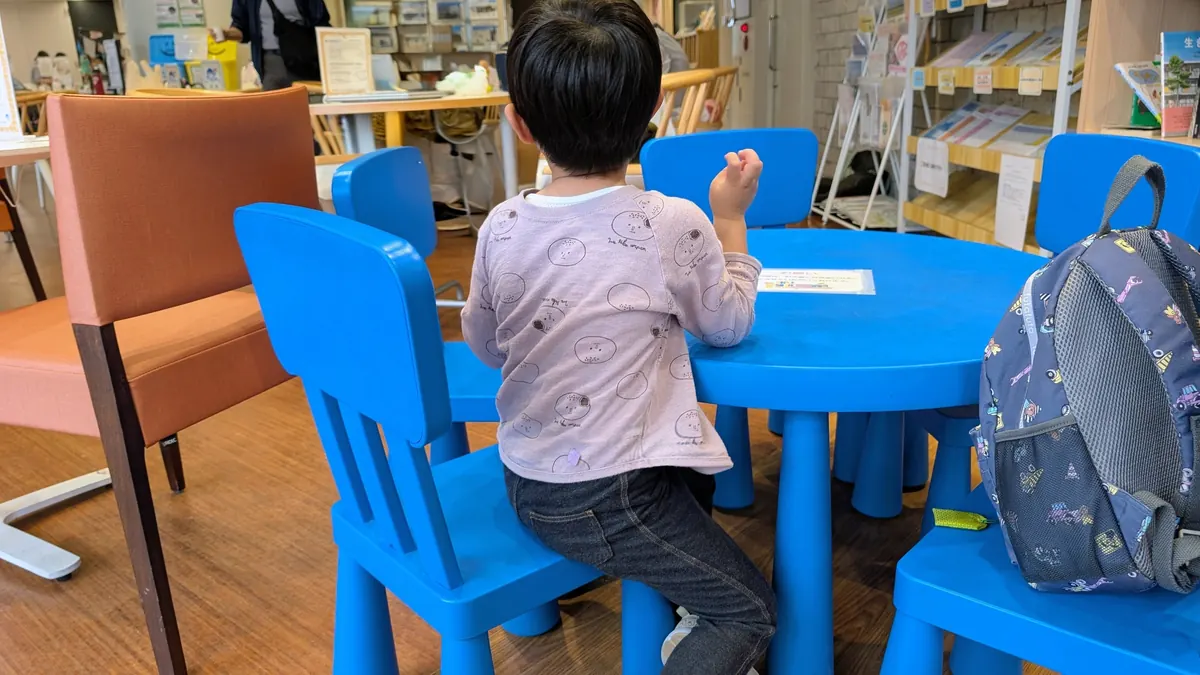 はまっぴひろばの子ども向け図書コーナー｜青いテーブルで本を楽しむ子ども