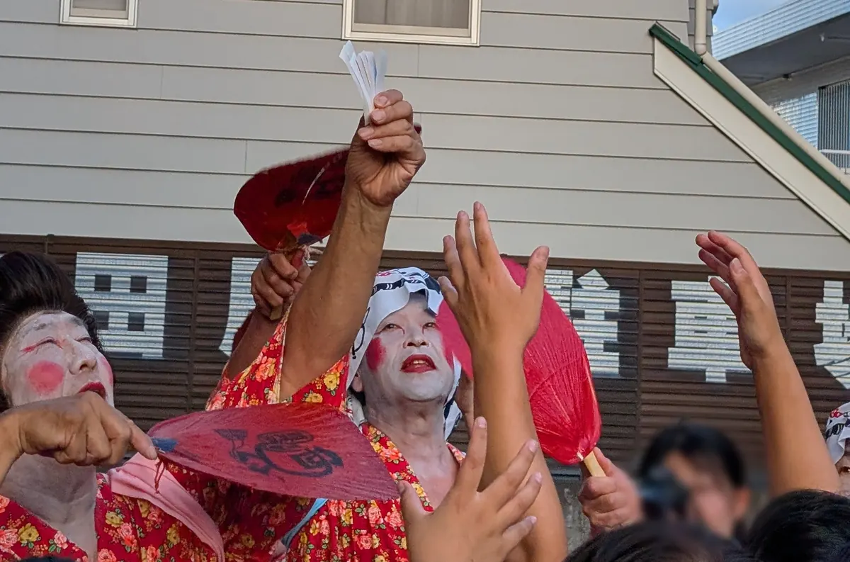 お札まきの瞬間｜踊り手が渋うちわで五色の神札を空に撒く