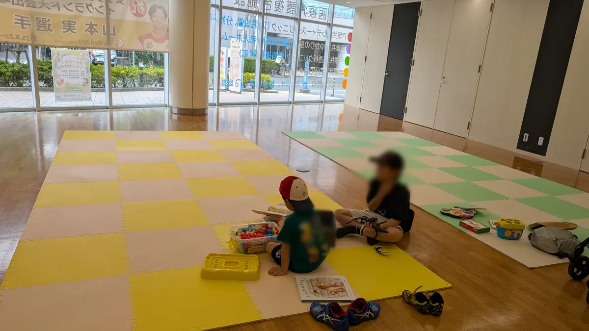 はまっぴひろばあそび広場の室内風景|黄色と緑のマットエリアで遊ぶ子どもたち