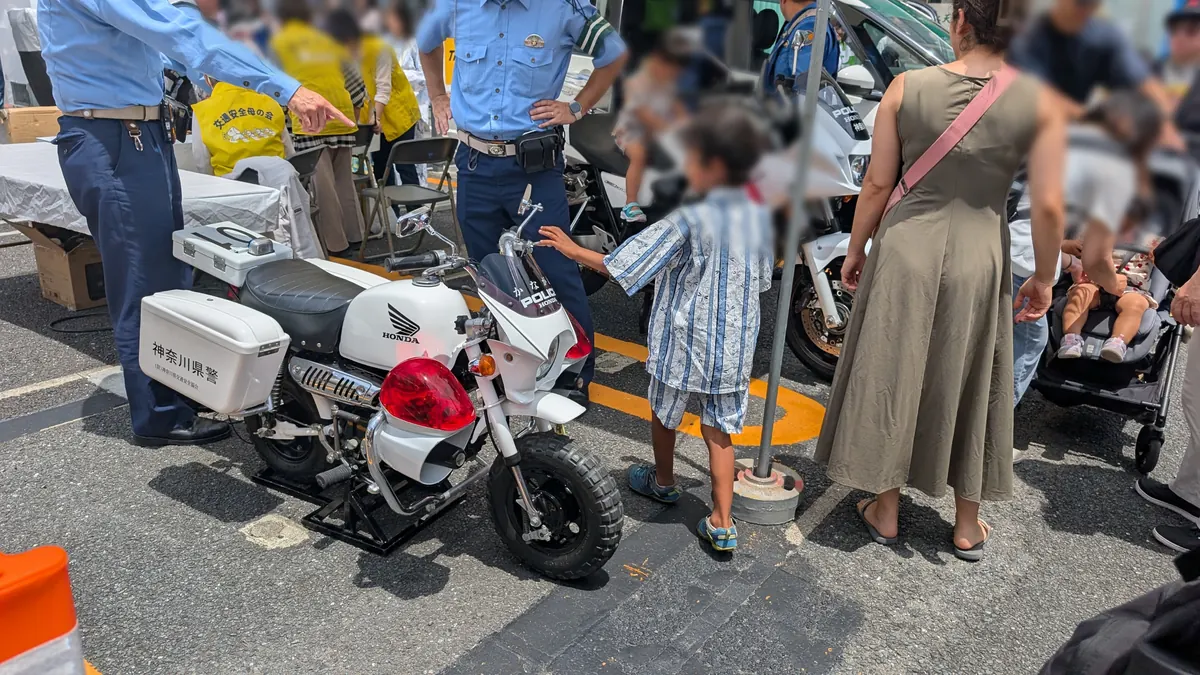 とつか夏まつりの神奈川県警ブース｜白バイにまたがる子ども