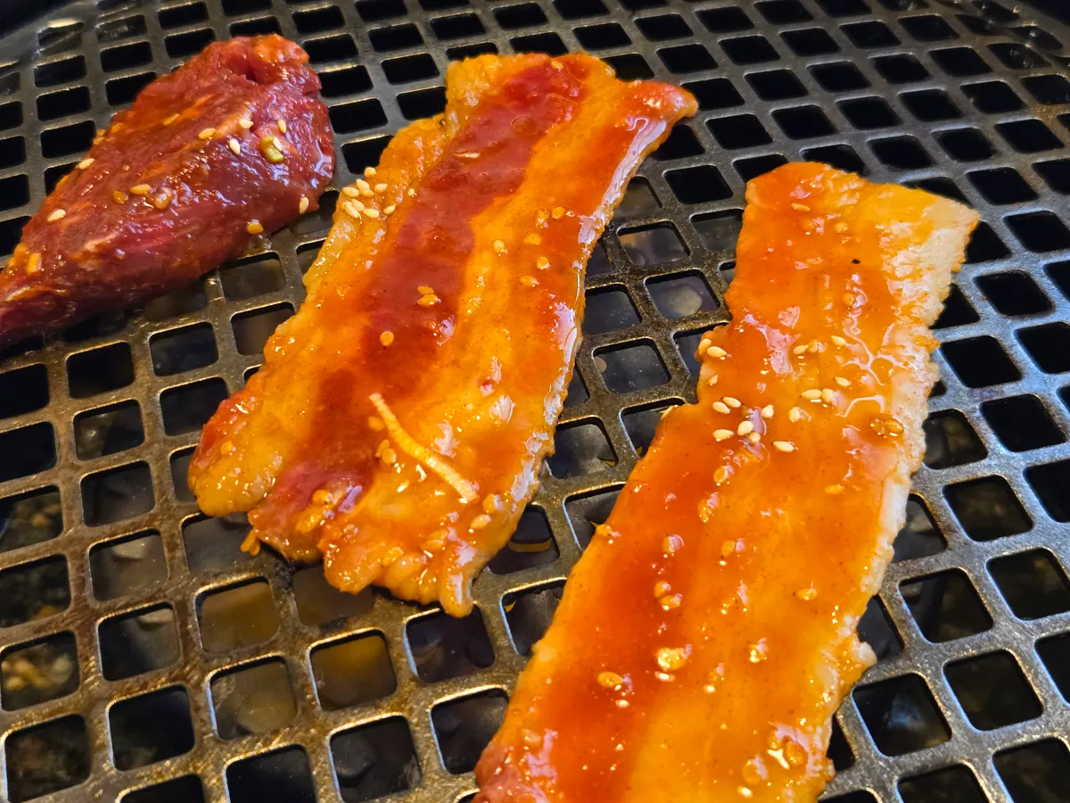 ロースターの網にのせた焼き始めの焼肉