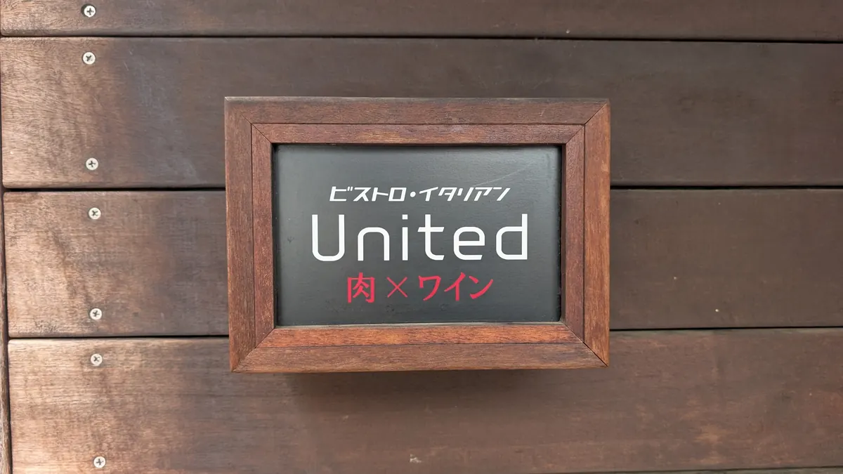 肉×ワイン ビストロ・イタリアン ユナイテッドの看板|戸塚町の外壁に掲げられたロゴプレート