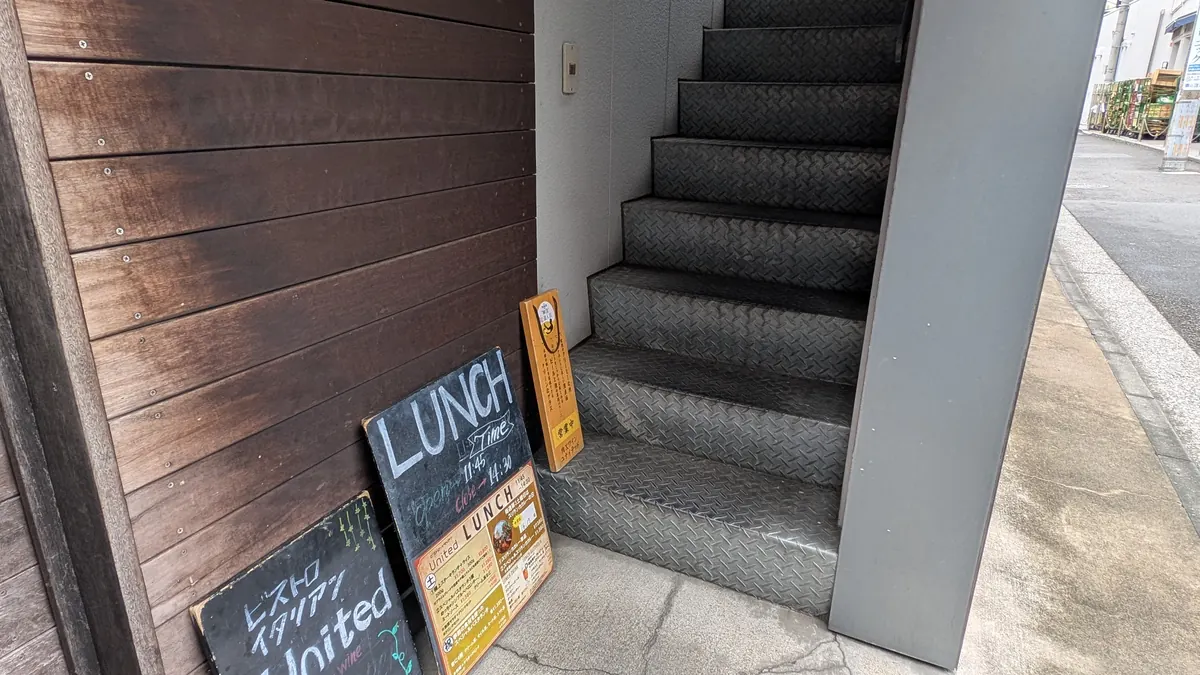 ユナイテッド入口の階段とランチ営業案内板|戸塚駅徒歩4分の2階店舗