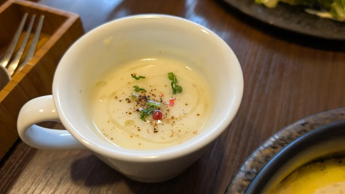 ランチに付いてくるスープ。白いマグカップに入った、クリーム色のなめらかなスープ