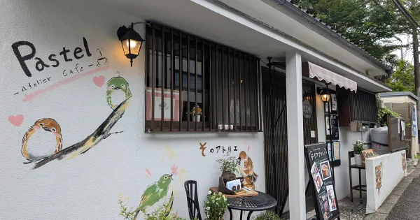 アトリエカフェパステルの外観。壁に店名ロゴと小鳥のイラストが描かれた戸塚町の古民家カフェ